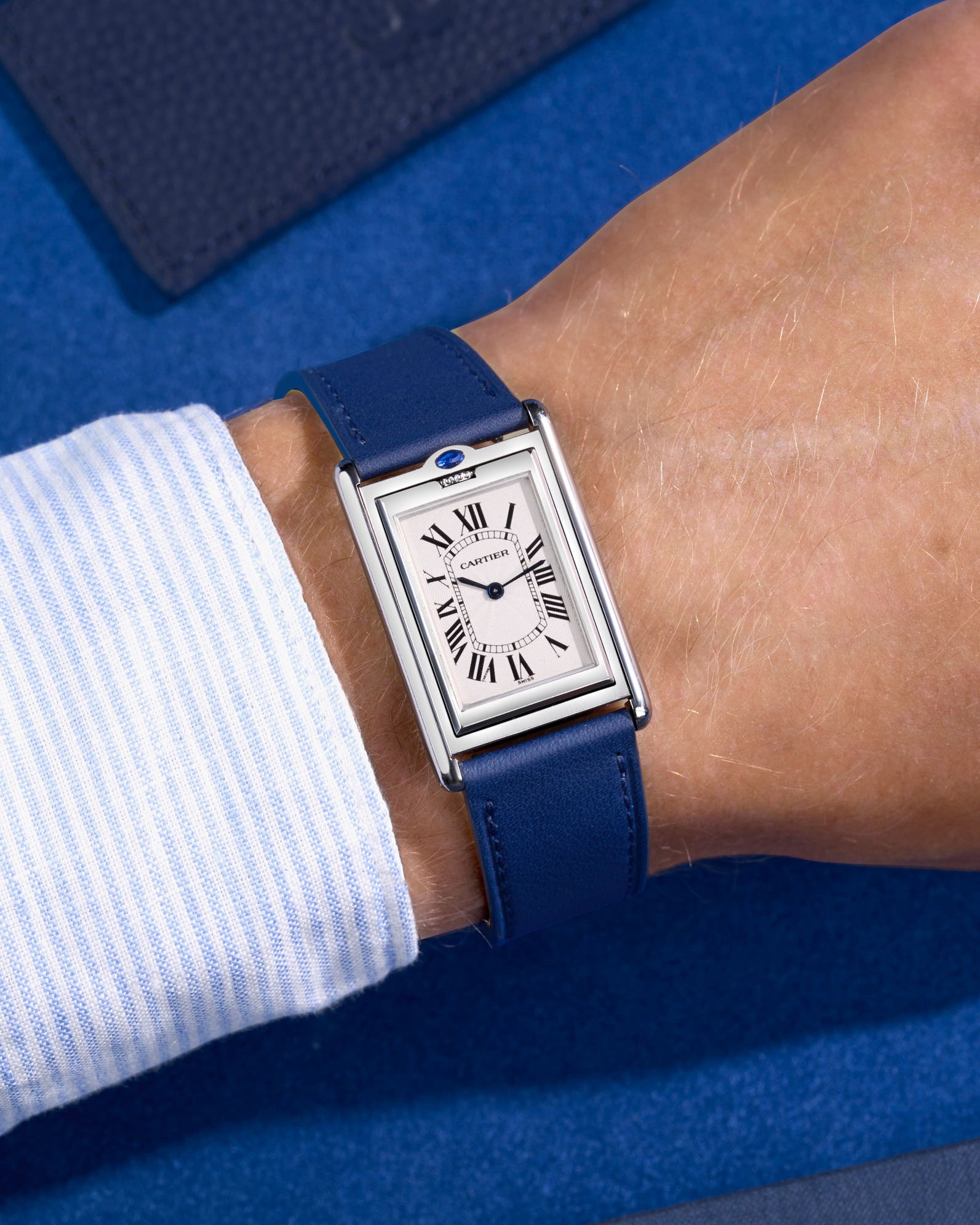 Cariter Basculante on a navy blue cowhide leather watch strap on a wrist with a suede background