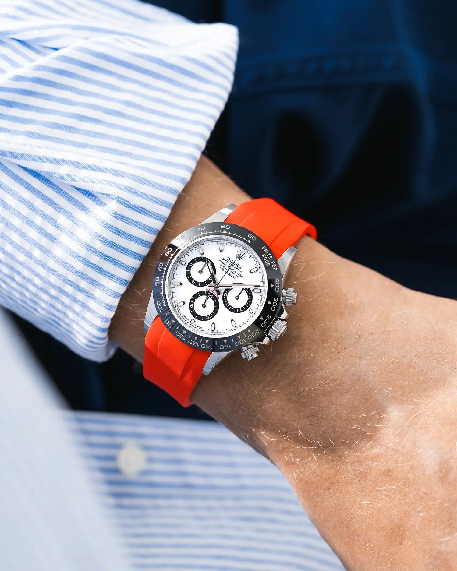 Red integrated FKM rubber strap with original clasp on Rolex Daytona 116500 white dial ceramic bezel wrist shot with blue and white shirt