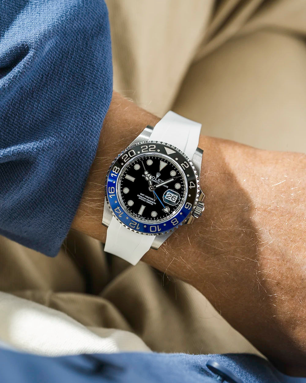 Close-up of a person wearing a Rolex GMT Master 2 batman model watch with a blue jacket sleeve and a white FKM rubber watch strap from Wristbuddys