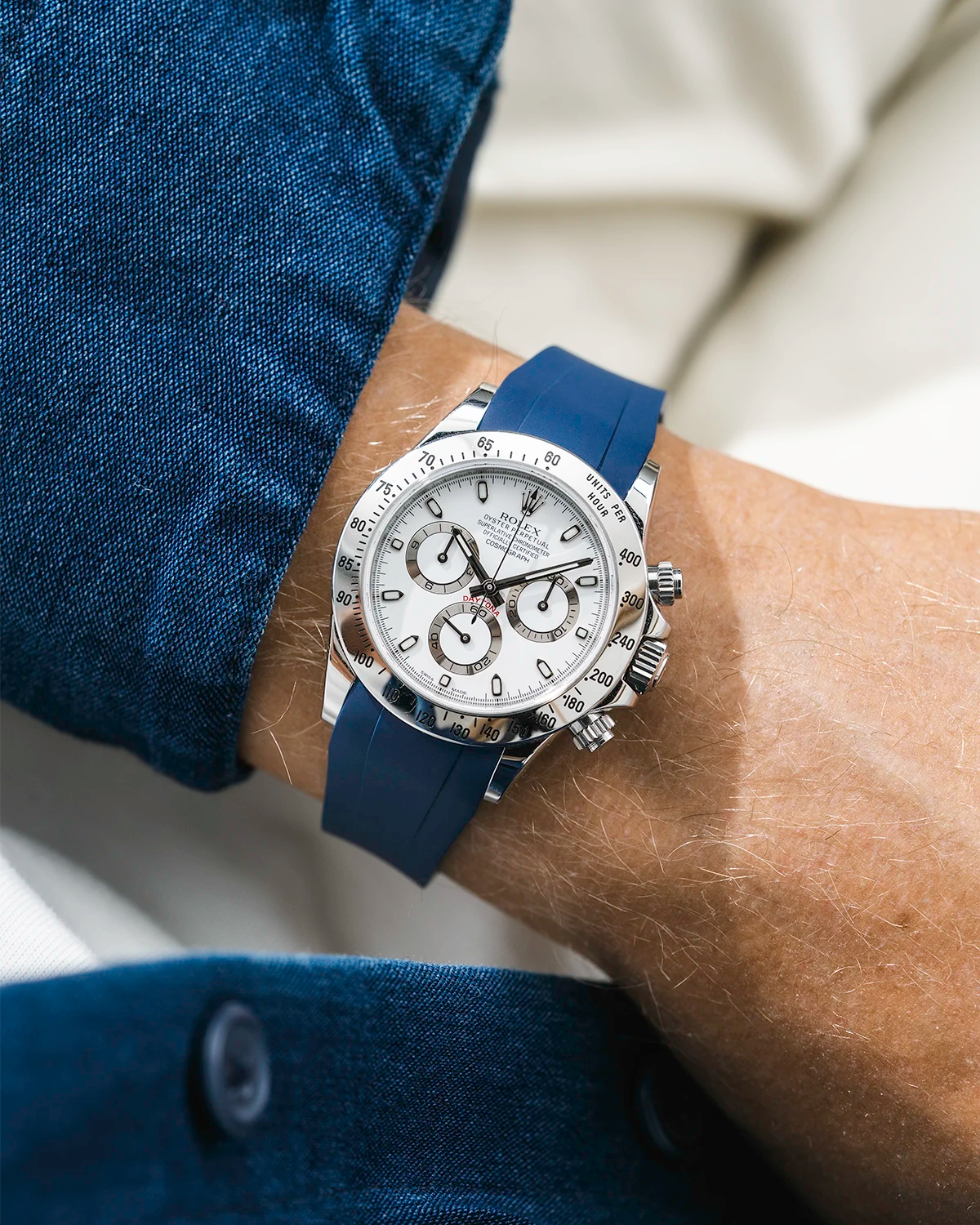 Close-up of a person wearing a white Rolex Daytona watch with a blue jacket sleeve and a FKM rubber watch strap from Wristbuddys