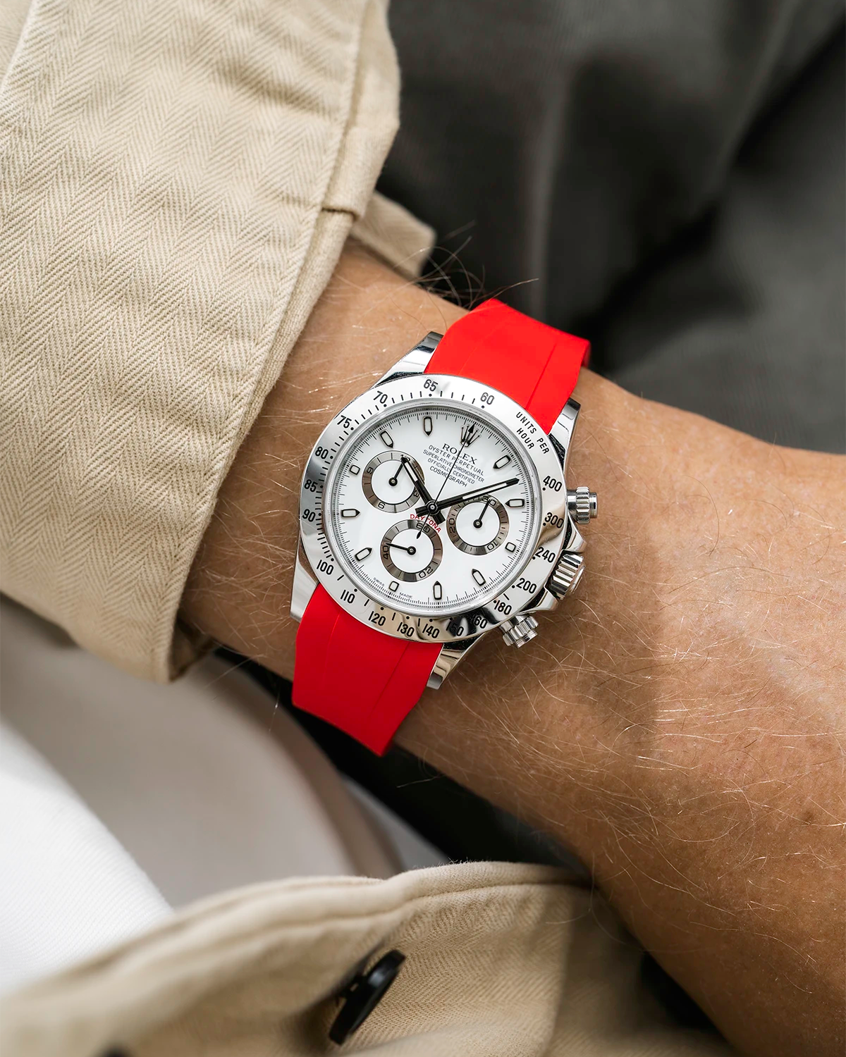 Close-up of a person wearing a white Rolex Daytona watch with a beige jacket sleeve and a red FKM rubber watch strap from Wristbuddys