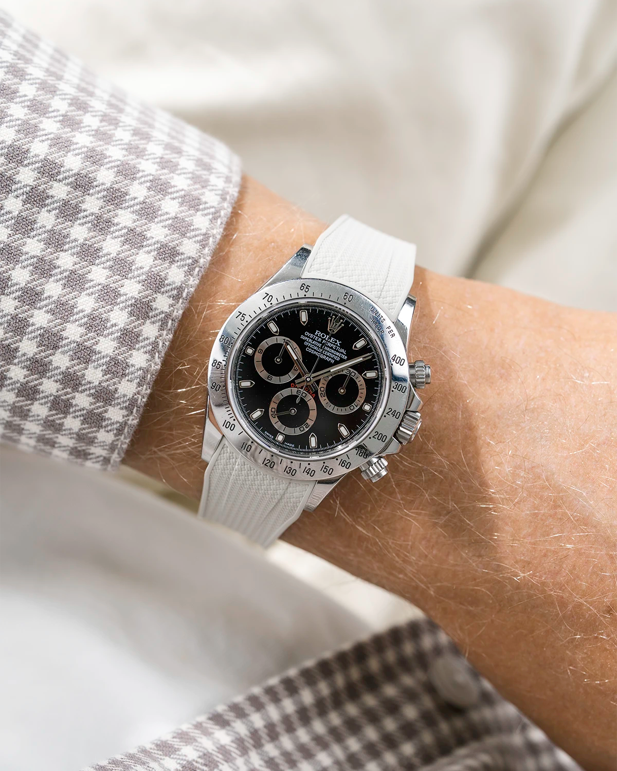 Close-up of a person wearing a black Rolex Daytona watch with a beige white stiped shirt sleeve and a beige vertech FKM rubber watch strap from Wristbuddys