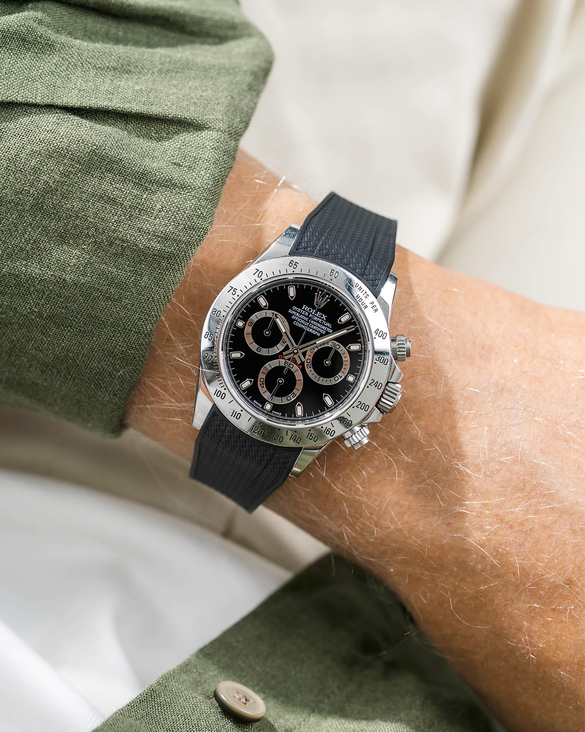 Close-up of a person wearing a black Rolex Daytona watch with a green stiped shirt sleeve and a black vertech FKM rubber watch strap from Wristbuddys
