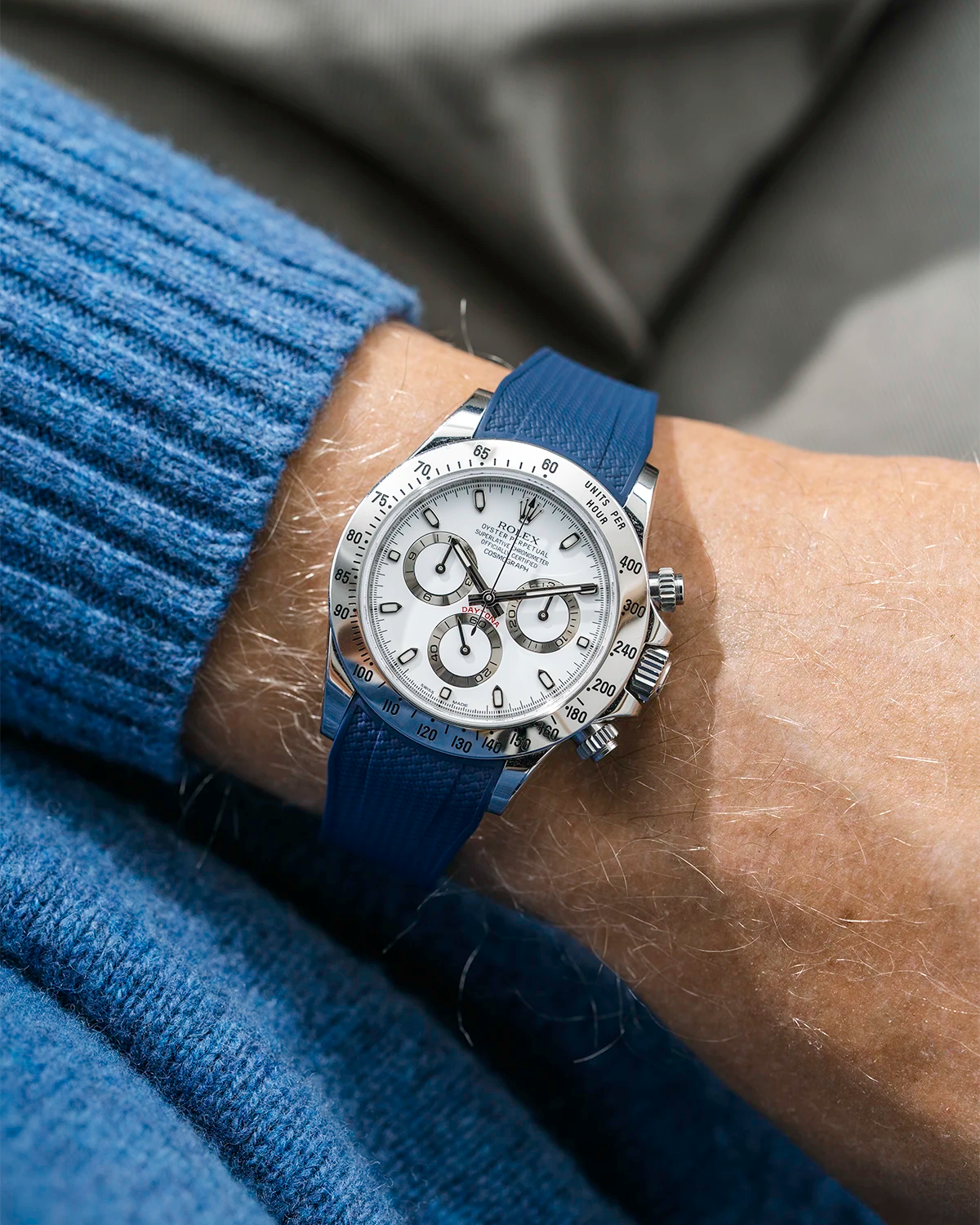 Close-up of a person wearing a white Rolex Daytona watch with a light blue stiped shirt sleeve and a dark blue vertech FKM rubber watch strap from Wristbuddys