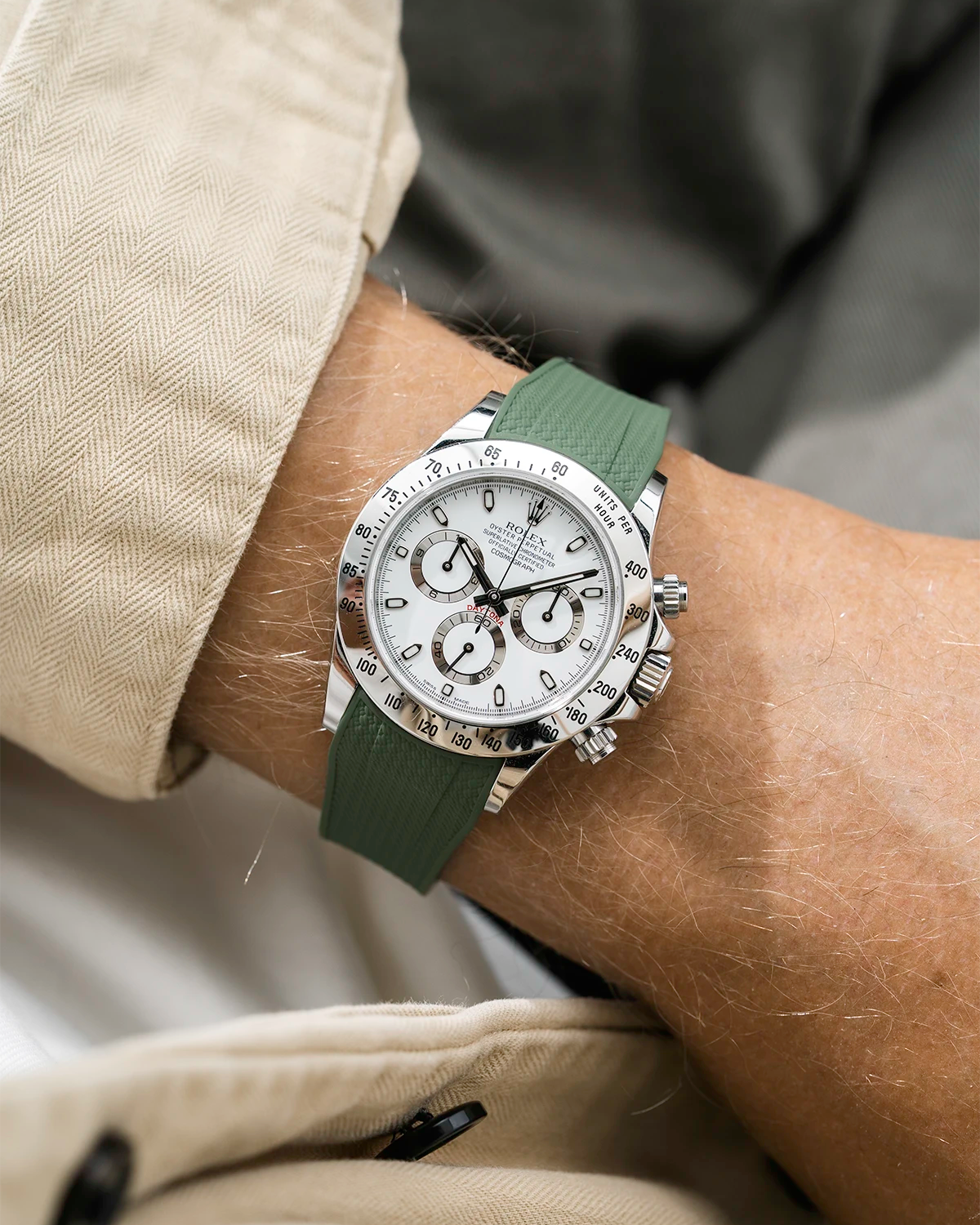 Close-up of a person wearing a white Rolex Daytona watch with a beige stiped shirt sleeve and a green vertech FKM rubber watch strap from Wristbuddys