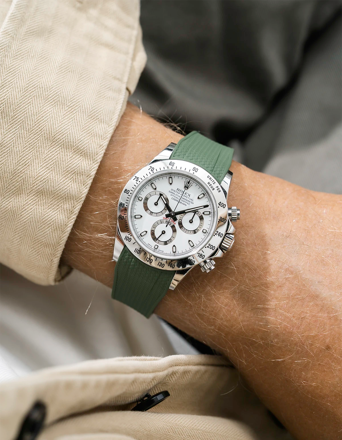 Close-up of a person wearing a white Rolex Daytona watch with a beige stiped shirt sleeve and a green vertech FKM rubber watch strap from Wristbuddys