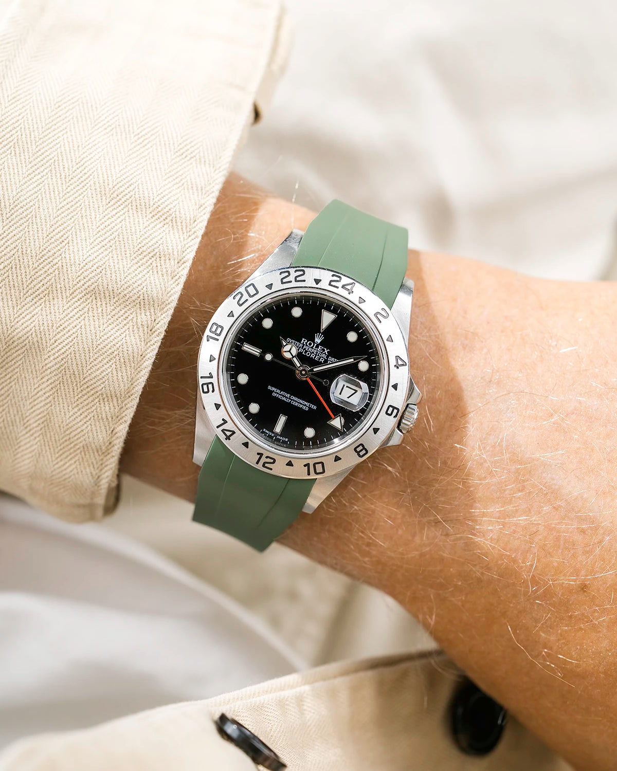 Close-up of a person wearing a Rolex Explorer 2 16570 model watch with a beige jacket sleeve and a green FKM rubber watch strap from Wristbuddys