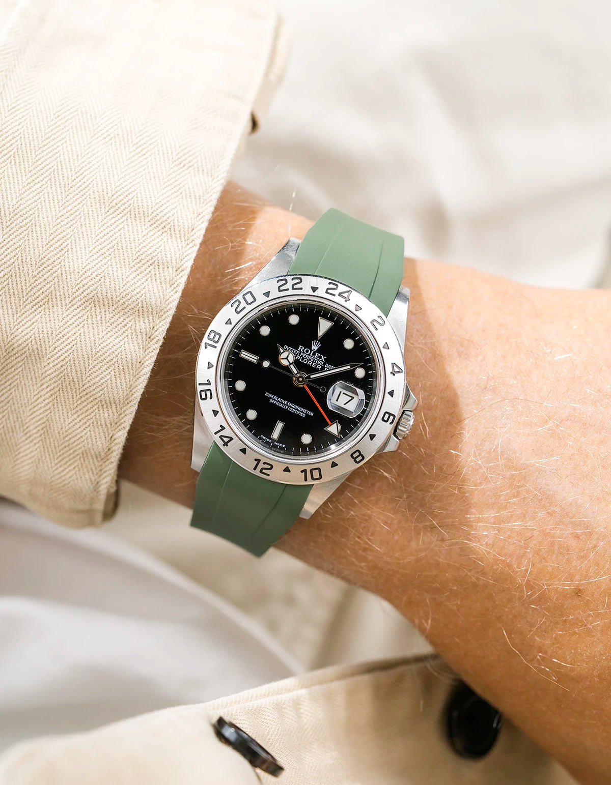 Close-up of a person wearing a Rolex Explorer 2 16570 model watch with a beige jacket sleeve and a green FKM rubber watch strap from Wristbuddys