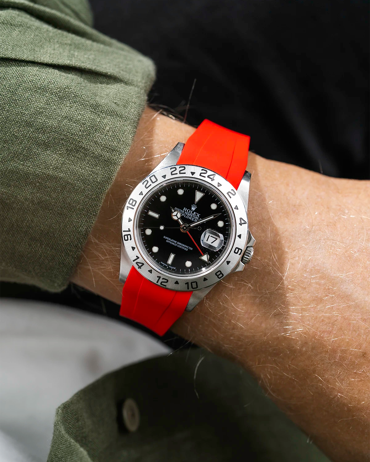 Close-up of a person wearing a Rolex Explorer 2 16570 model watch with a green jacket sleeve and a red FKM rubber watch strap from Wristbuddys