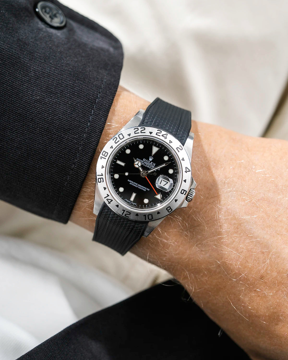 Close-up of a person wearing a Rolex Explorer 2 16570 model watch with a black jacket sleeve and a black Vertech FKM rubber watch strap from Wristbuddys