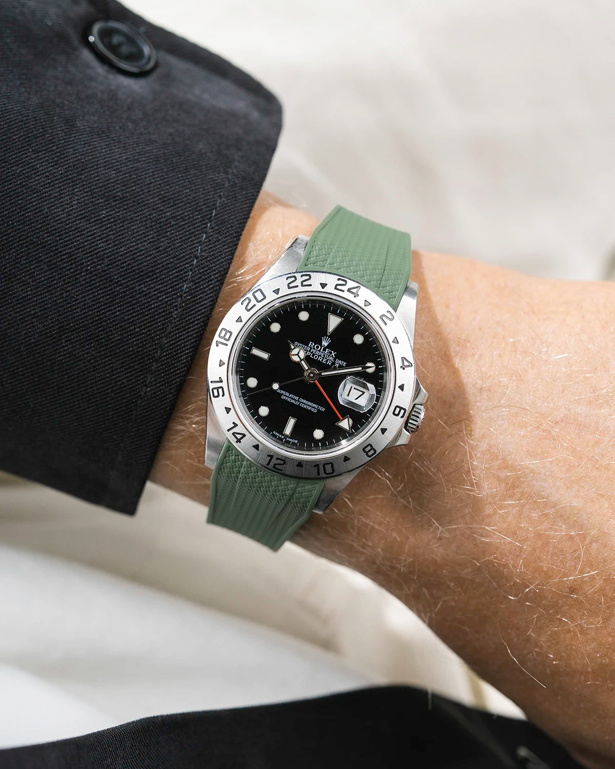Close-up of a person wearing a Rolex Explorer 2 16570 model watch with a black jacket sleeve and a green Vertech FKM rubber watch strap from Wristbuddys