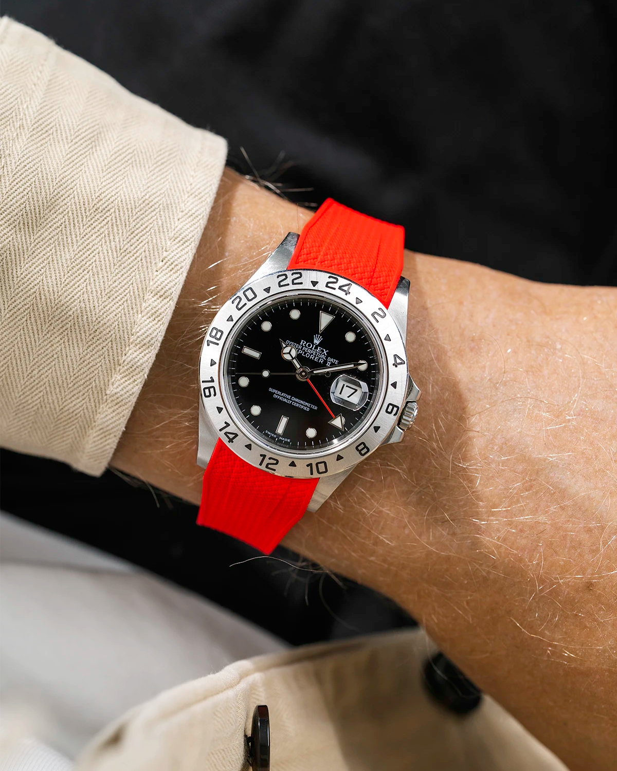 Close-up of a person wearing a Rolex Explorer 2 16570 model watch with a beige jacket sleeve and a red Vertech FKM rubber watch strap from Wristbuddys