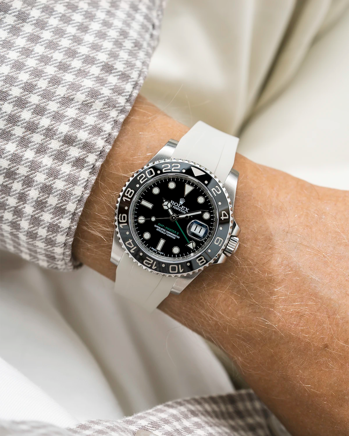 Close-up of a person wearing a Rolex GMT Master Green hand 116710 model watch with white and beige jacket sleeve and a beige FKM rubber watch strap from Wristbuddys