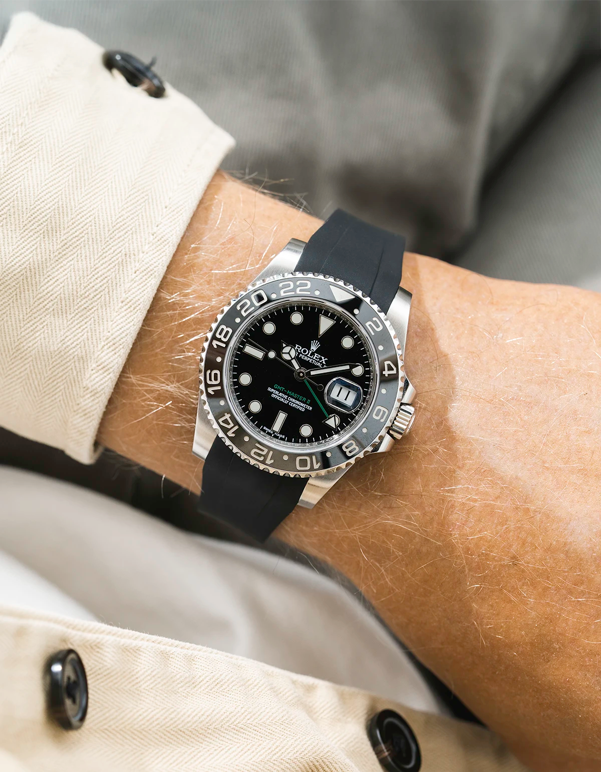 Close-up of a person wearing a Rolex GMT Master Green hand 116710 model watch with beige jacket sleeve and a black FKM rubber watch strap from Wristbuddys