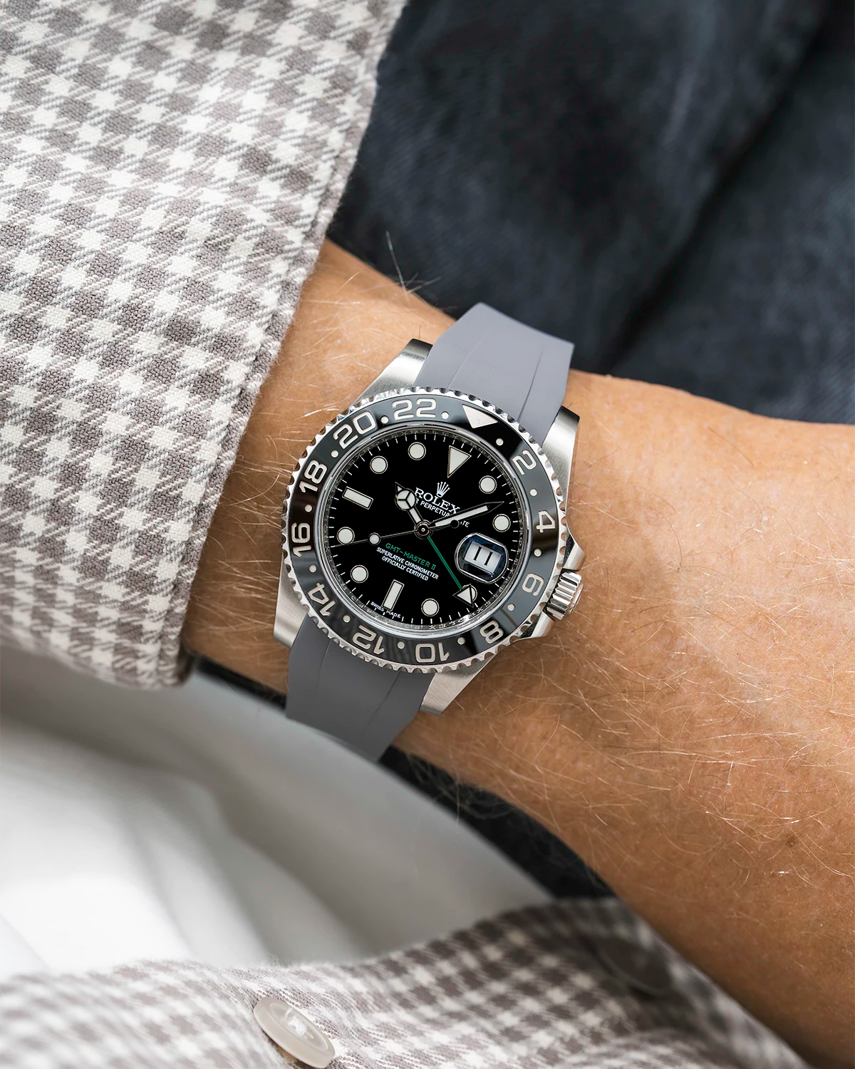 Close-up of a person wearing a Rolex GMT Master Green hand 116710 model watch with white and beige jacket sleeve and a grey FKM rubber watch strap from Wristbuddys