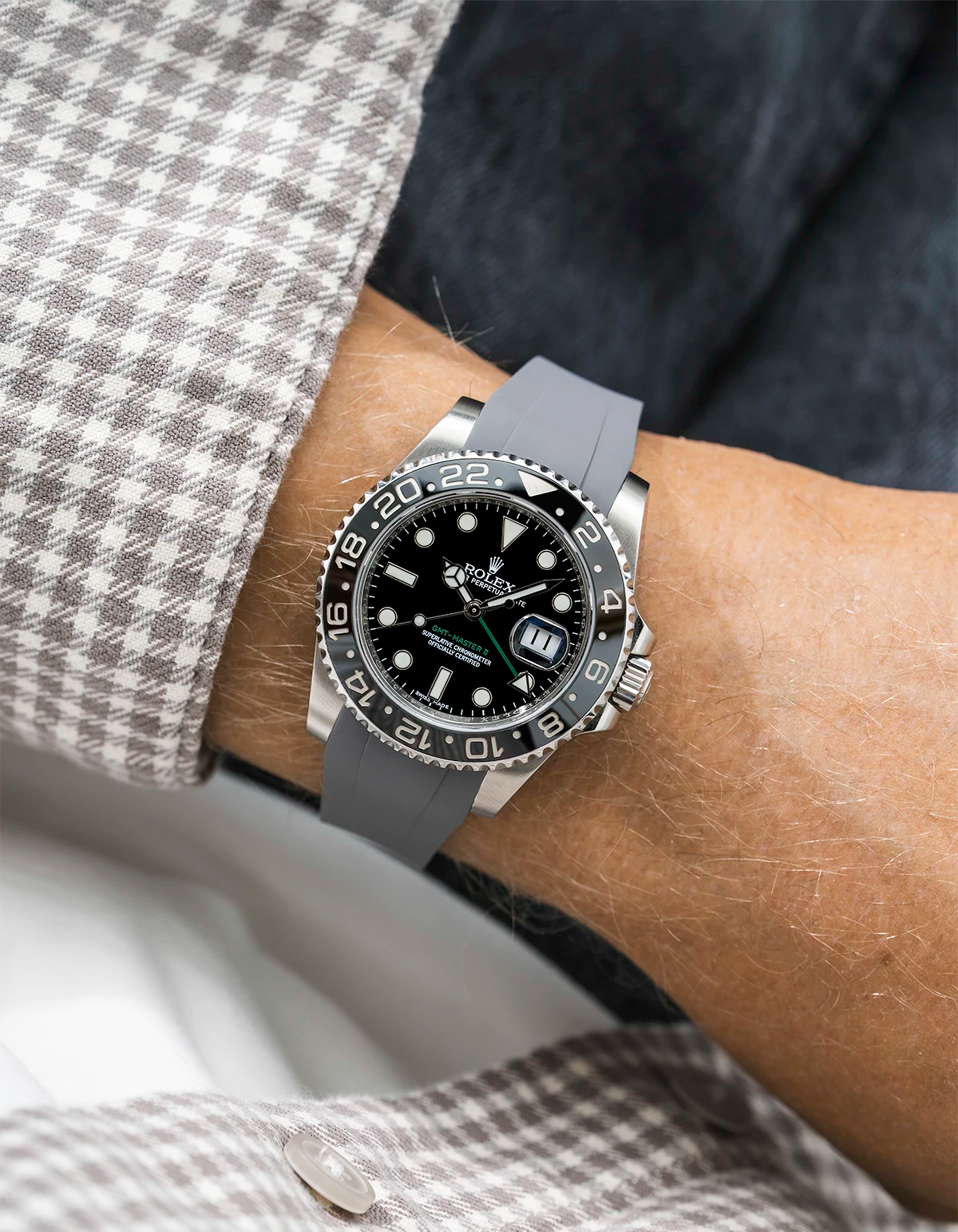 Close-up of a person wearing a Rolex GMT Master Green hand 116710 model watch with white and beige jacket sleeve and a grey FKM rubber watch strap from Wristbuddys