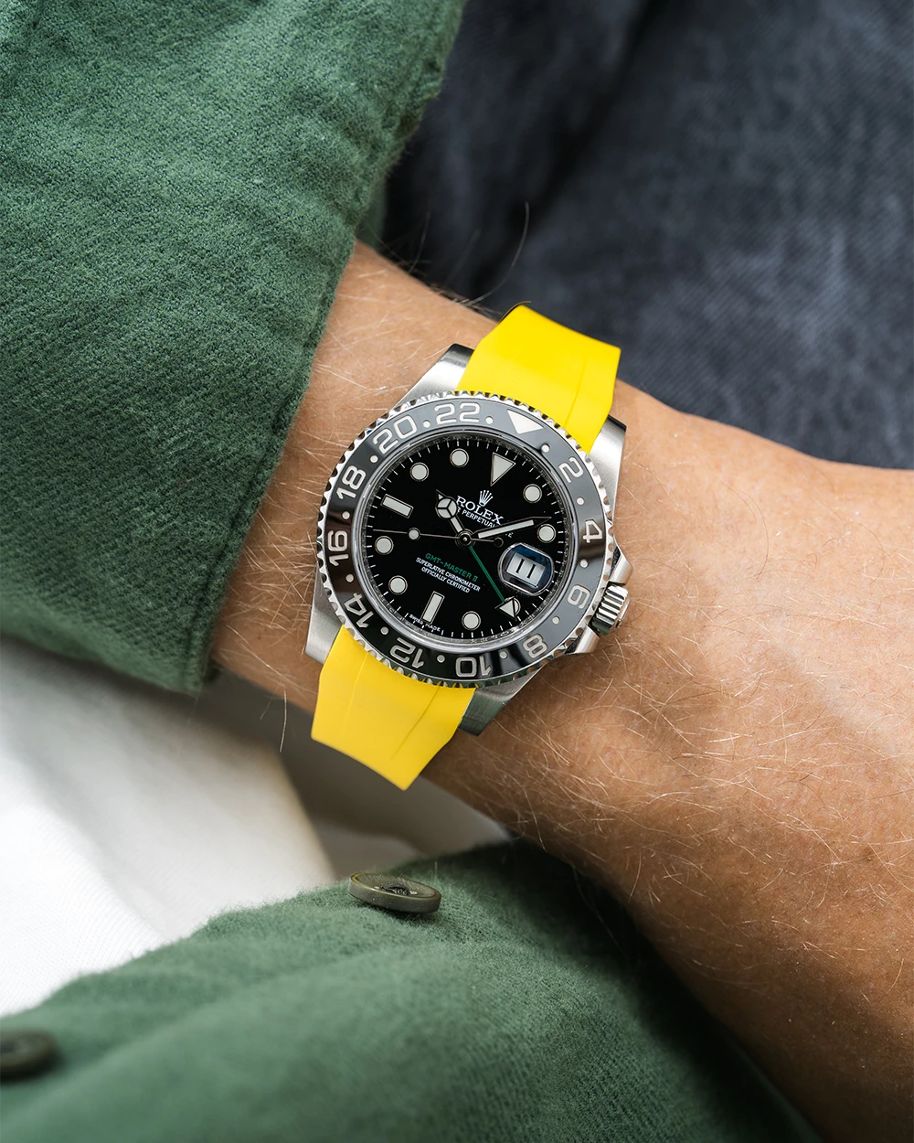 Close-up of a person wearing a Rolex GMT Master Green hand 116710 model watch with green jacket sleeve and a yellow FKM rubber watch strap from Wristbuddys
