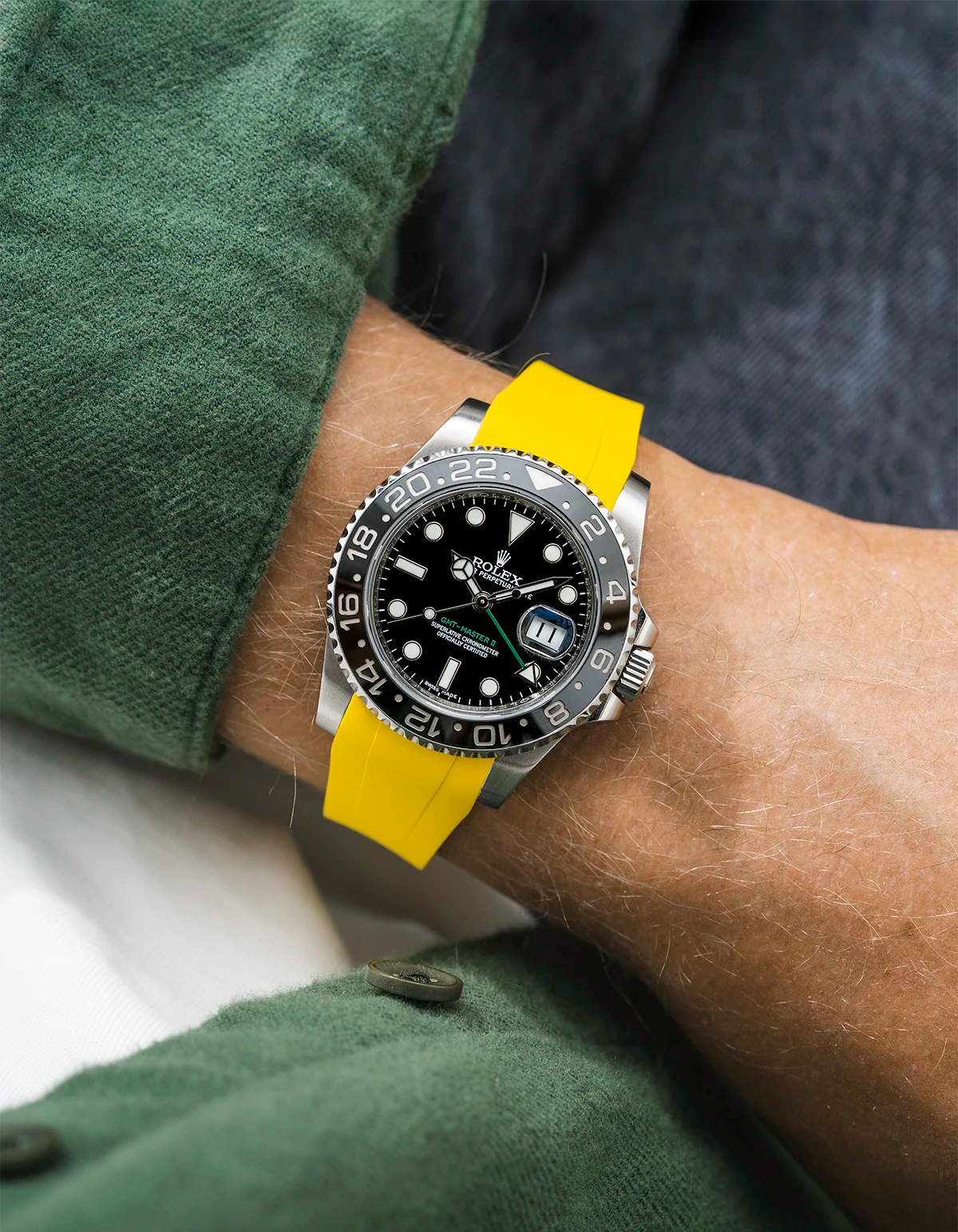 Close-up of a person wearing a Rolex GMT Master Green hand 116710 model watch with green jacket sleeve and a yellow FKM rubber watch strap from Wristbuddys