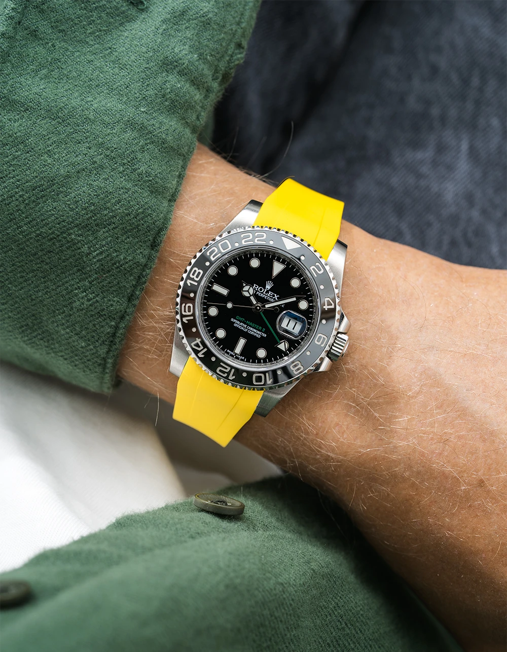 Close-up of a person wearing a Rolex GMT Master Green hand 116710 model watch with green jacket sleeve and a yellow FKM rubber watch strap from Wristbuddys