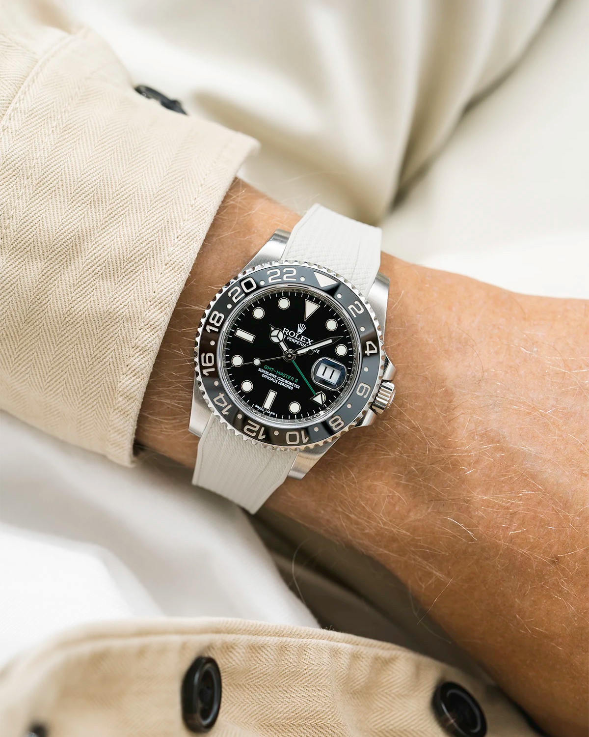 Close-up of a person wearing a Rolex GMT Master Green hand 116710 model watch with beige jacket sleeve and a beige vertech FKM rubber watch strap from Wristbuddys