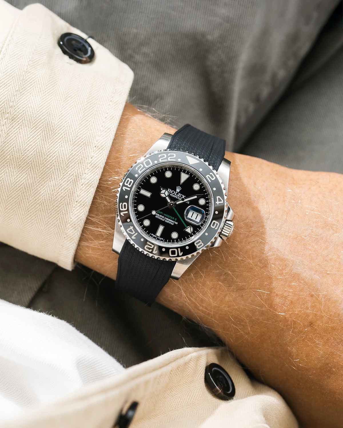 Close-up of a person wearing a Rolex GMT Master Green hand 116710 model watch with beige jacket sleeve and a black vertech FKM rubber watch strap from Wristbuddys