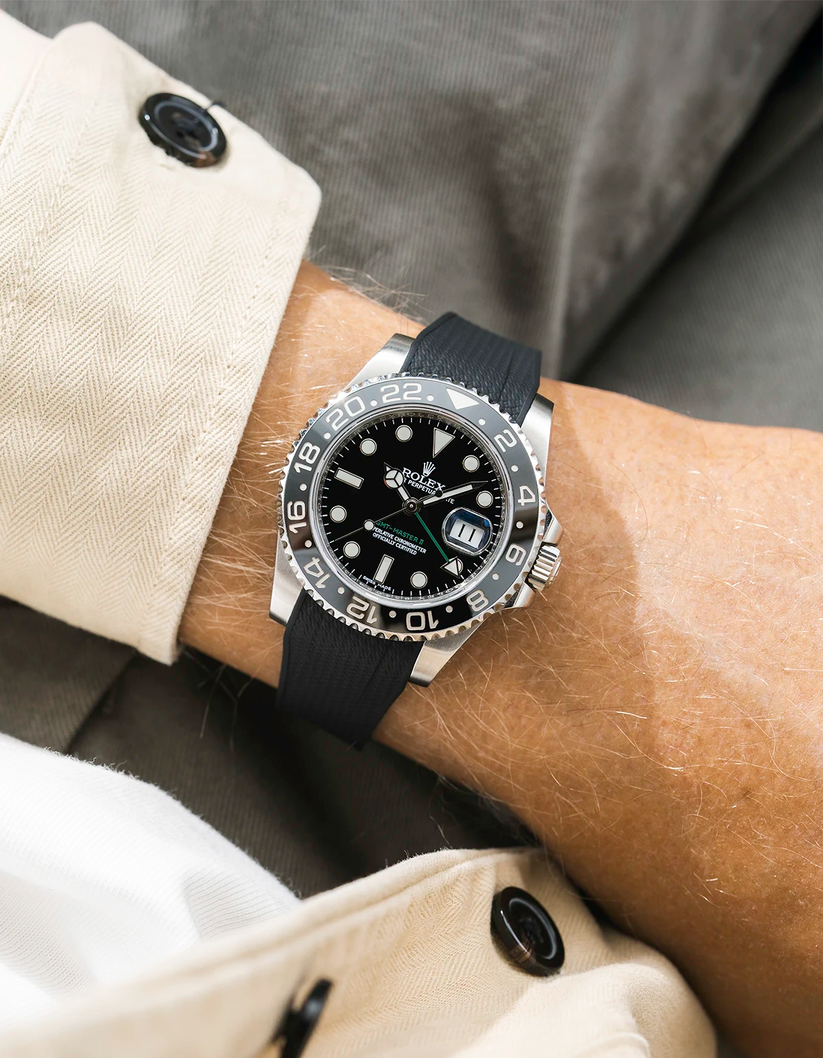 Close-up of a person wearing a Rolex GMT Master Green hand 116710 model watch with beige jacket sleeve and a black vertech FKM rubber watch strap from Wristbuddys