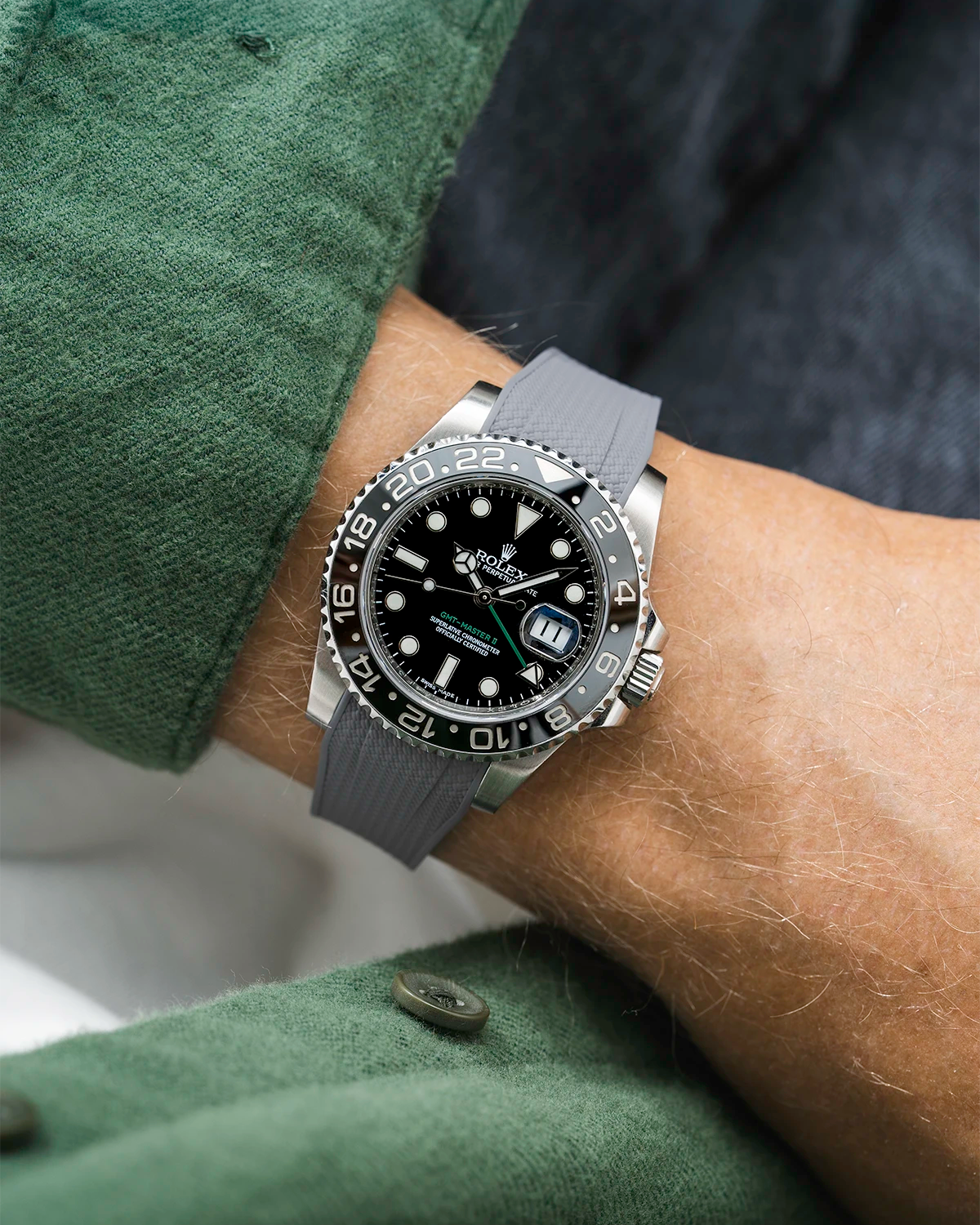 Close-up of a person wearing a Rolex GMT Master Green hand 116710 model watch with green jacket sleeve and a grey vertech FKM rubber watch strap from Wristbuddys