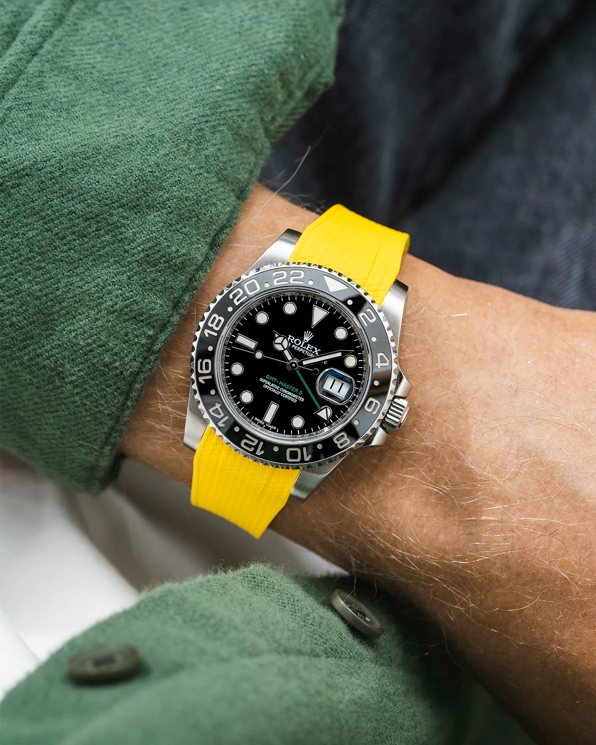 Close-up of a person wearing a Rolex GMT Master Green hand 116710 model watch with green jacket sleeve and a yellow vertech FKM rubber watch strap from Wristbuddys