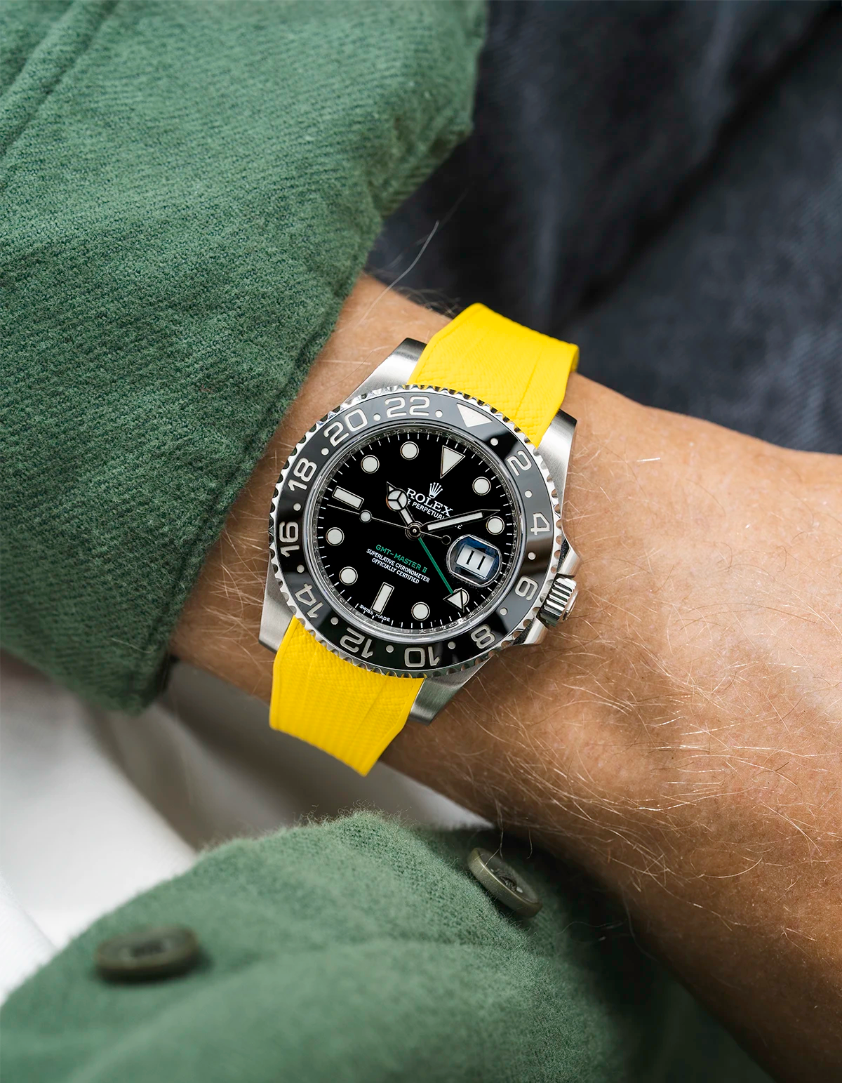 Close-up of a person wearing a Rolex GMT Master Green hand 116710 model watch with green jacket sleeve and a yellow vertech FKM rubber watch strap from Wristbuddys
