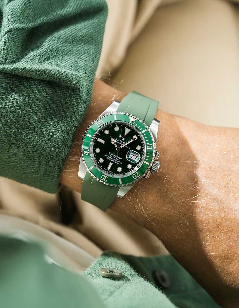 Close-up of a wrist wearing a Rolex Submariner on a Wristbuddys FKM Rubber watch strap & watch with a green face, against a blurred background.