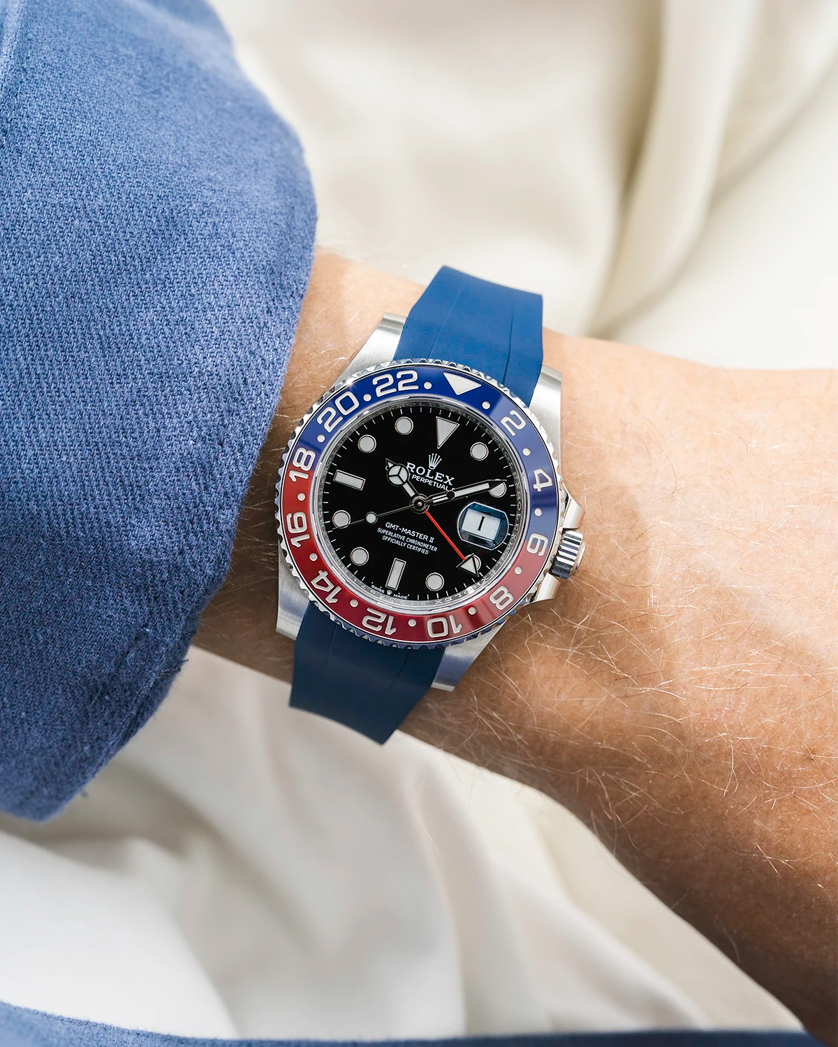 Close-up of a person wearing a Rolex GMT Master 2 Pepsi model watch with a blue jacket sleeve and a blue FKM rubber watch strap from Wristbuddys
