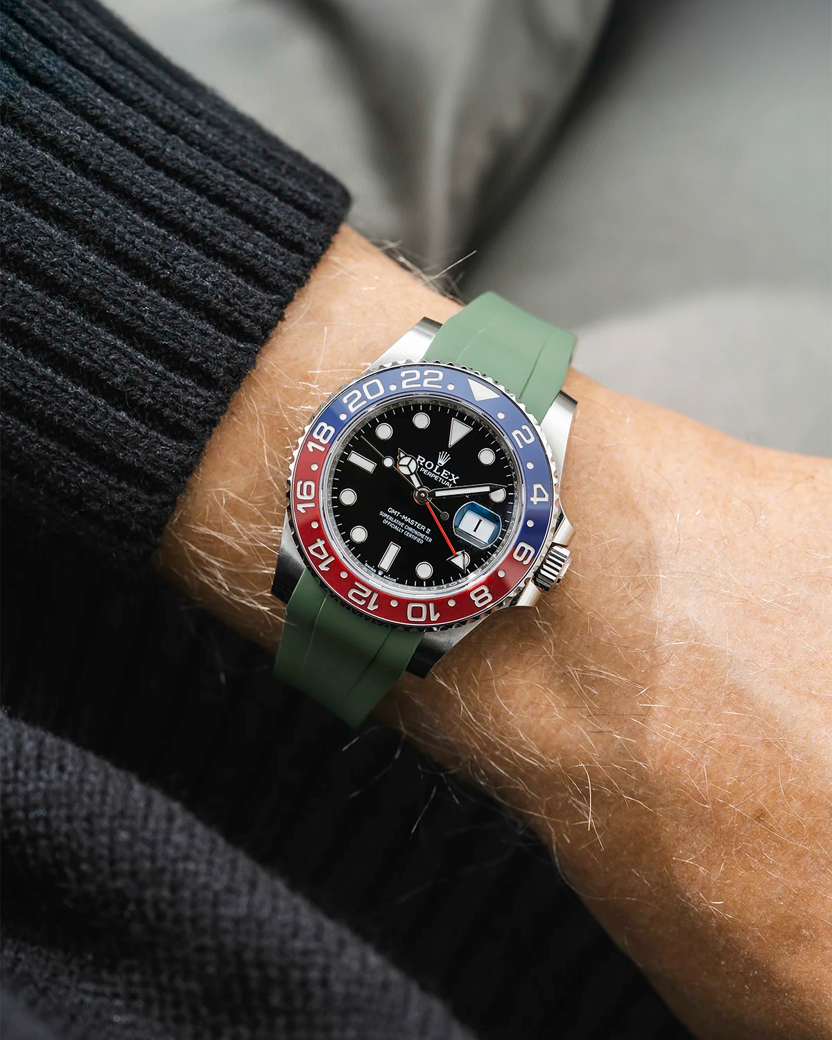 Close-up of a person wearing a Rolex GMT Master 2 Pepsi model watch with a blak jacket sleeve and a black FKM rubber watch strap from Wristbuddys