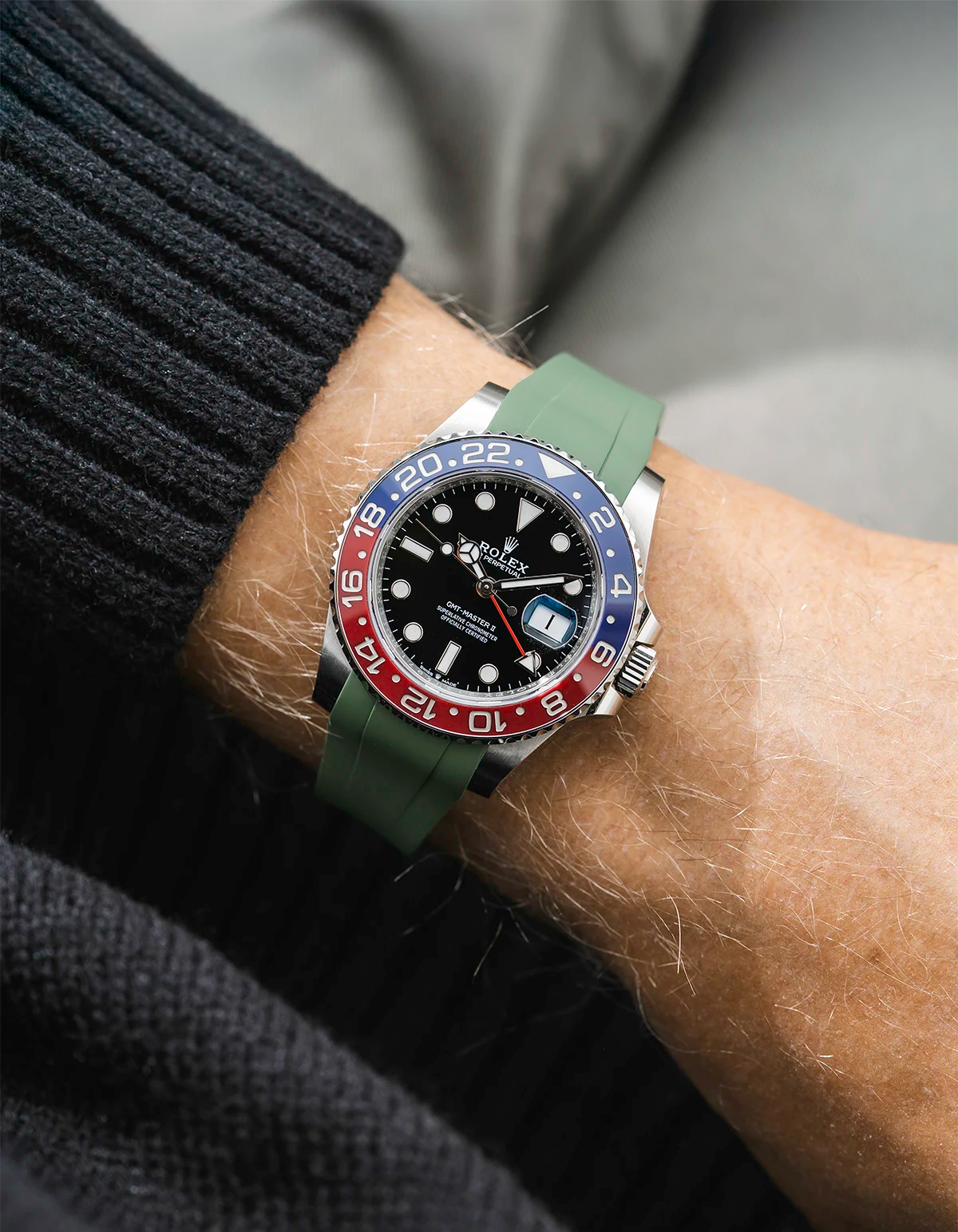 Close-up of a person wearing a Rolex GMT Master 2 Pepsi model watch with a blak jacket sleeve and a black FKM rubber watch strap from Wristbuddys