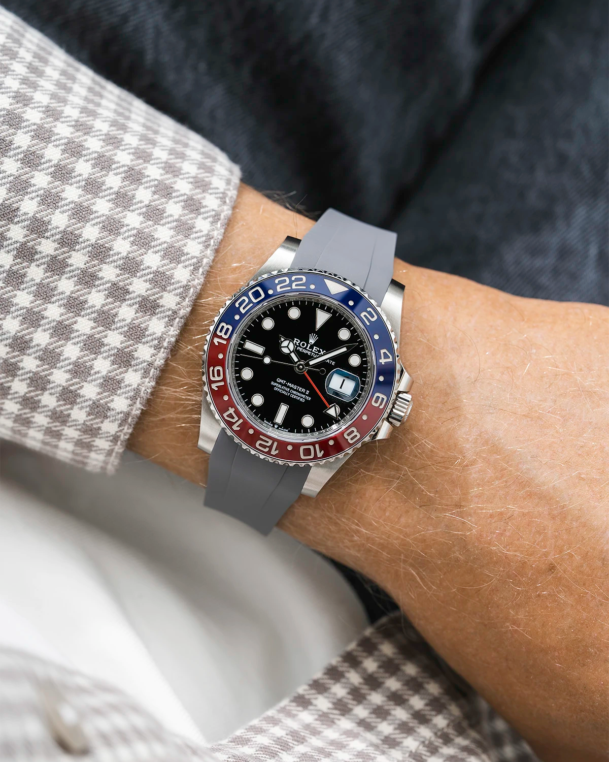 Close-up of a person wearing a Rolex GMT Master 2 Pepsi model watch with a beige white jacket sleeve and a grey FKM rubber watch strap from Wristbuddys