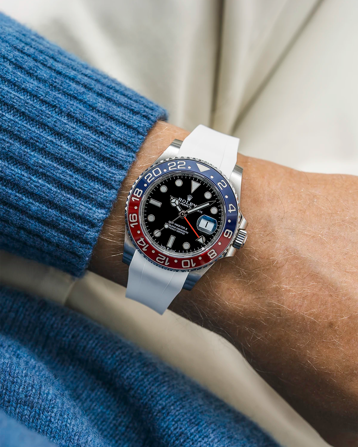 Close-up of a person wearing a Rolex GMT Master 2 Pepsi model watch with a blue jacket sleeve and a white FKM rubber watch strap from Wristbuddys