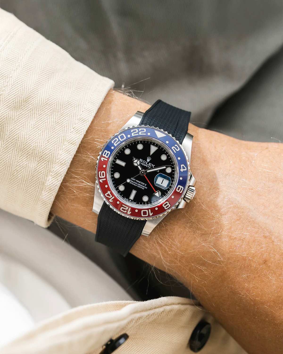 Close-up of a person wearing a Rolex GMT Master 2 Pepsi model watch with beige jacket sleeve and a black vertech FKM rubber watch strap from Wristbuddys