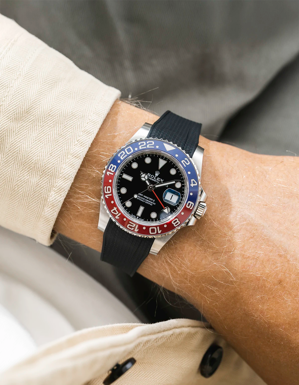 Close-up of a person wearing a Rolex GMT Master 2 Pepsi model watch with beige jacket sleeve and a black vertech FKM rubber watch strap from Wristbuddys