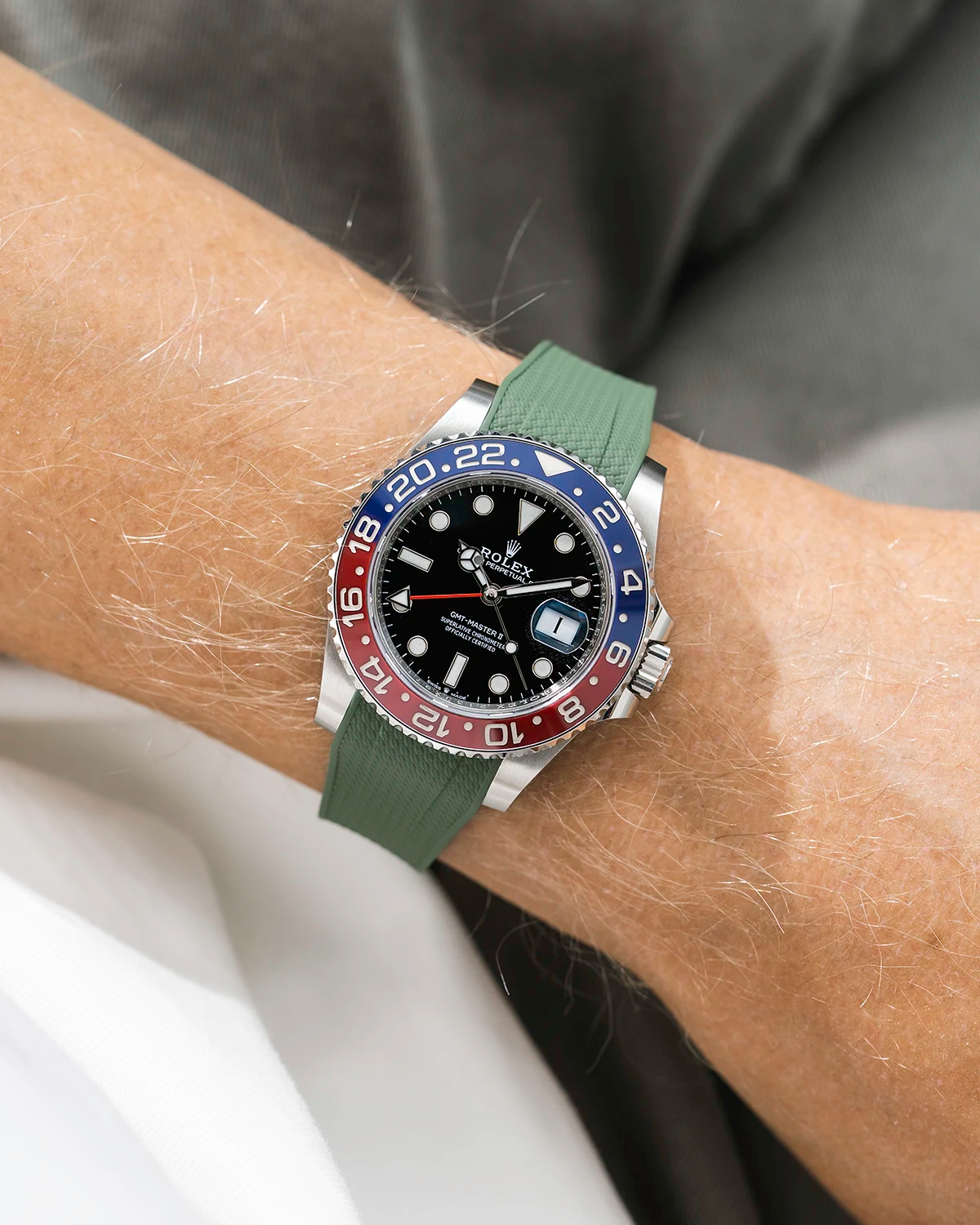 Close-up of a person wearing a Rolex GMT Master 2 Pepsi model watch with sleeve and a green vertech FKM rubber watch strap from Wristbuddys