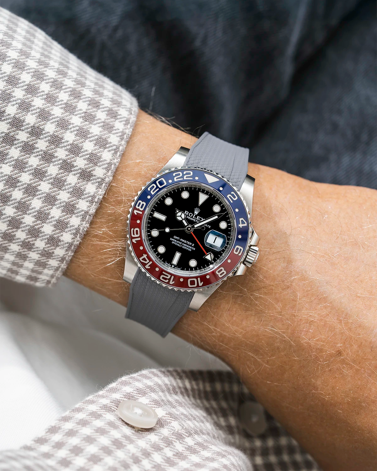 Close-up of a person wearing a Rolex GMT Master 2 Pepsi model watch with beige white jacket sleeve and a grey vertech FKM rubber watch strap from Wristbuddys