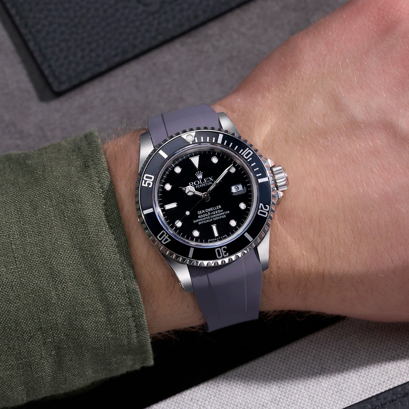 Rolex Sea-Dweller 16600 with grey FKM rubber strap from Wristbuddys worn on wrist with green shirt