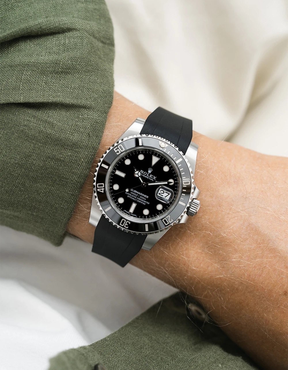 Black Rolex Submariner on a Wristbuddys FKM Rubber watch strap with a silver case on a person's wrist, wearing a green sleeve.