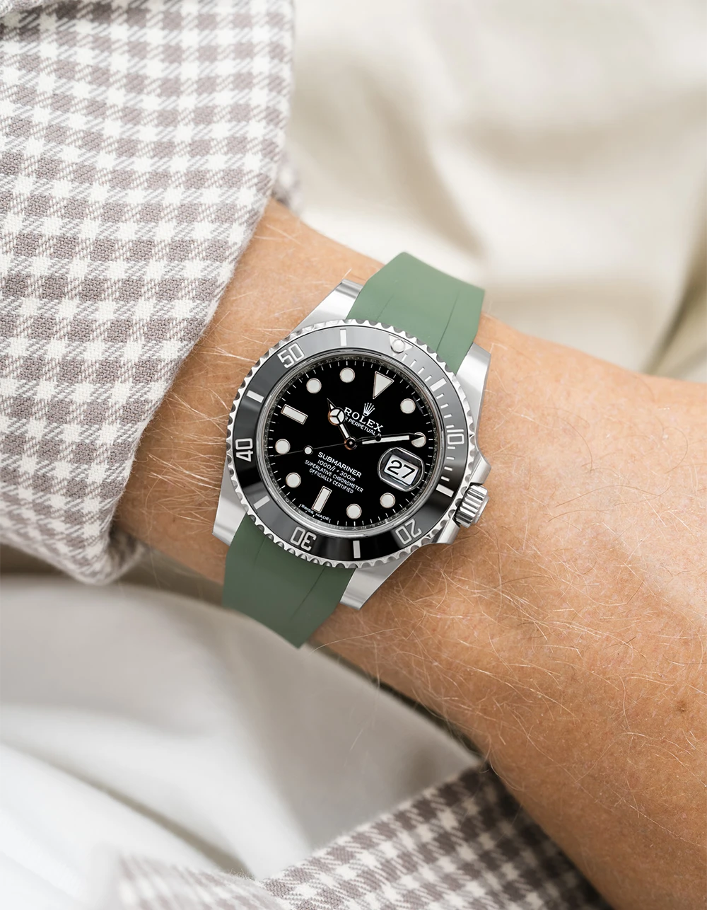 Wrist wearing a Rolex Submariner on a Wristbuddys FKM Rubber watch strap with a green strap and checkered shirt sleeve.