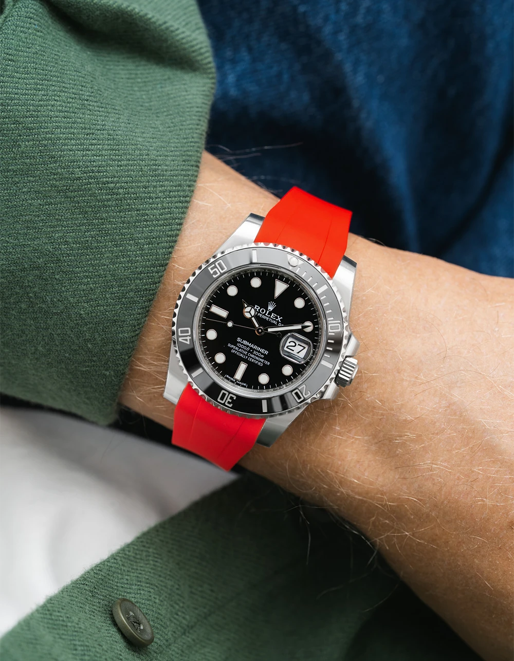 Rolex Submariner on a red Wristbuddys FKM Rubber watch strap on a wrist, wearing a green shirt.
