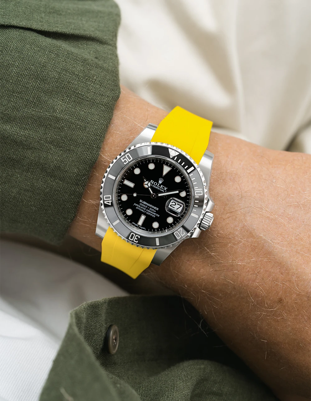Rolex Submariner on a yellow Wristbuddys FKM Rubber watch strap on a wrist, wearing a green jacket.