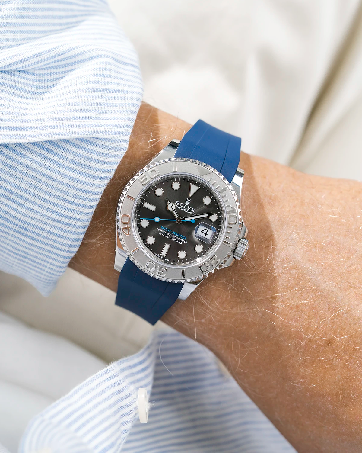 Close-up of a person wearing a Rolex YachtMaster 2 126622 / 116622 model watch with a light blue shirt sleeve and a blue FKM rubber watch strap from Wristbuddys