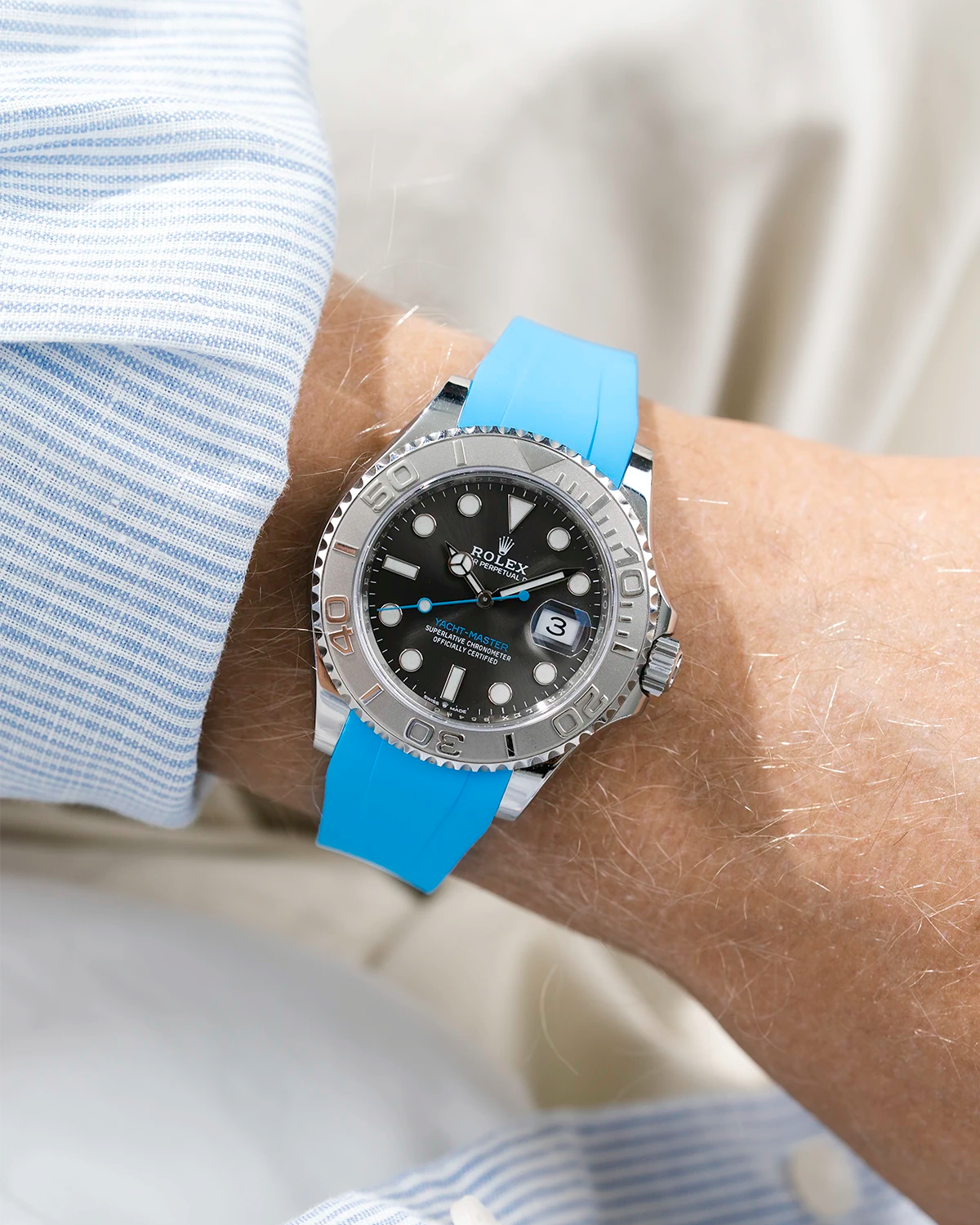 Close-up of a person wearing a Rolex YachtMaster 2 126622 / 116622 model watch with a light blue shirt sleeve and a capri FKM rubber watch strap from Wristbuddys