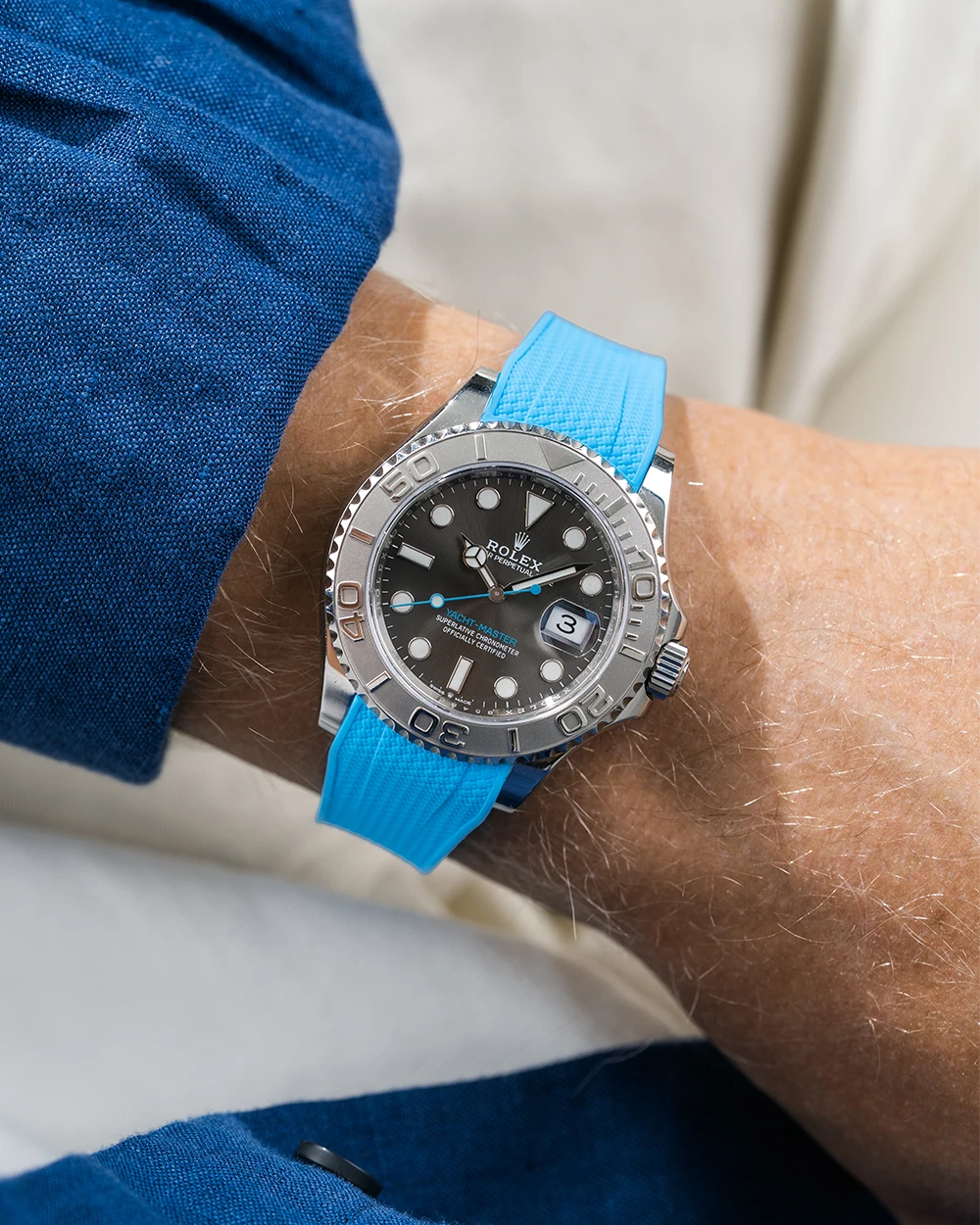 Close-up of a person wearing a Rolex YachtMaster 2 126622 / 116622 model watch with a blue shirt sleeve and a Capri Blue Vertech FKM rubber watch strap from Wristbuddys