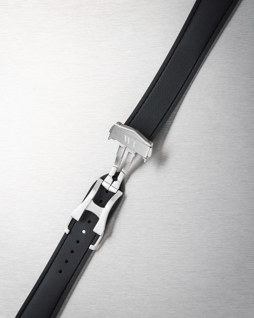Black leather belt with silver buckle on a metallic surface