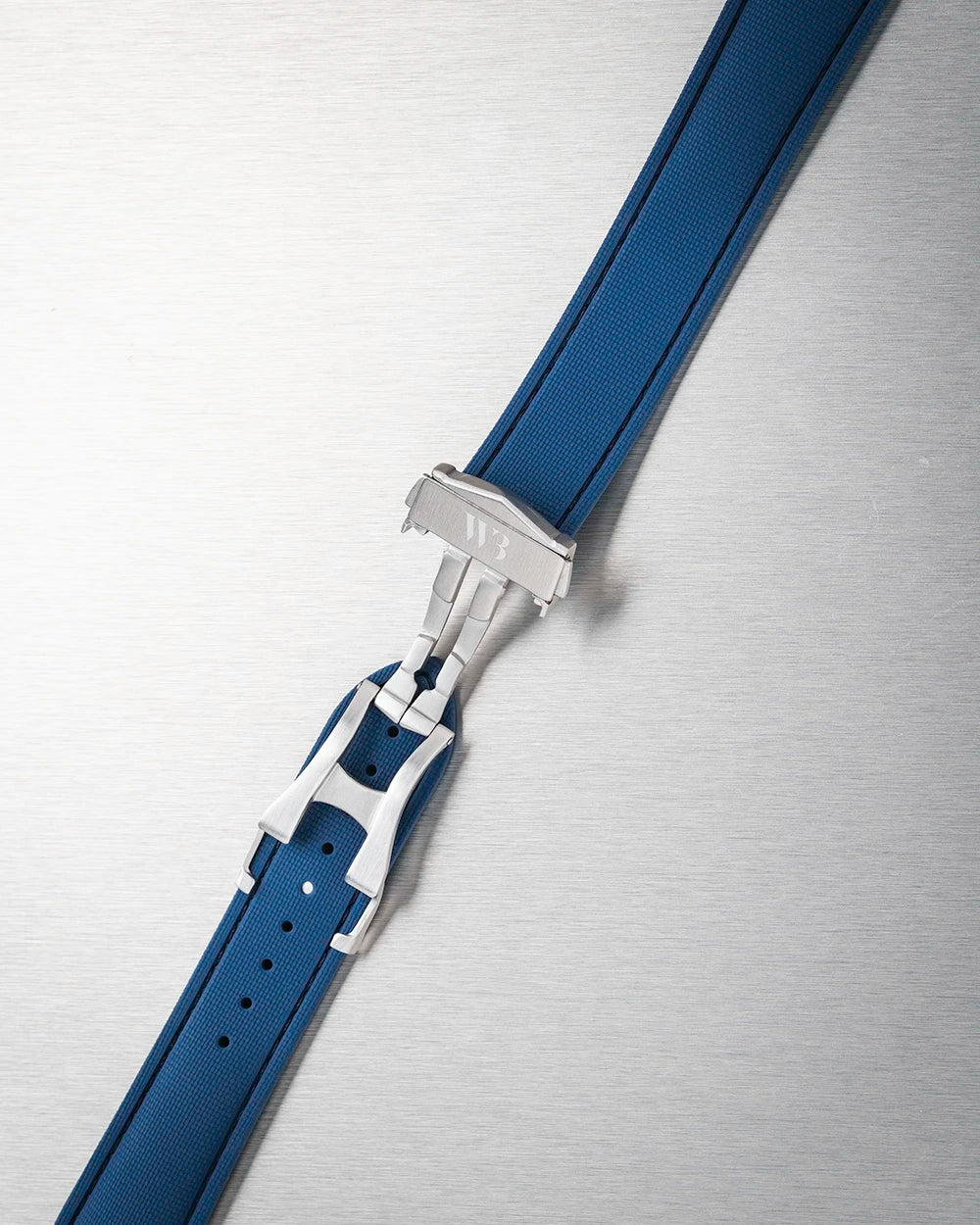 Close-up of a blue watch strap with silver buckle on a metallic surface