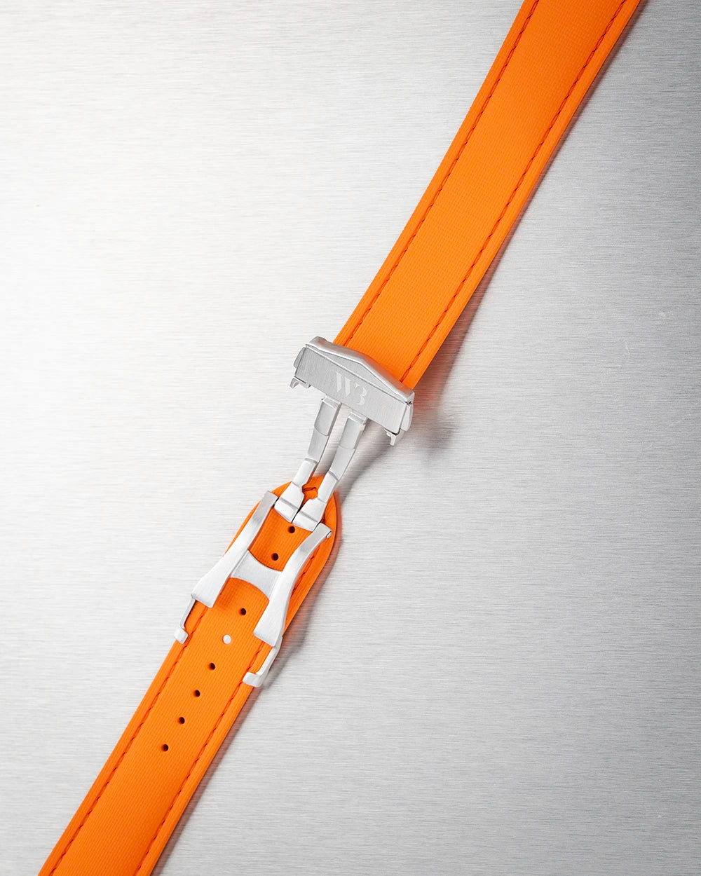 Orange watch strap with silver clasp on a textured gray background